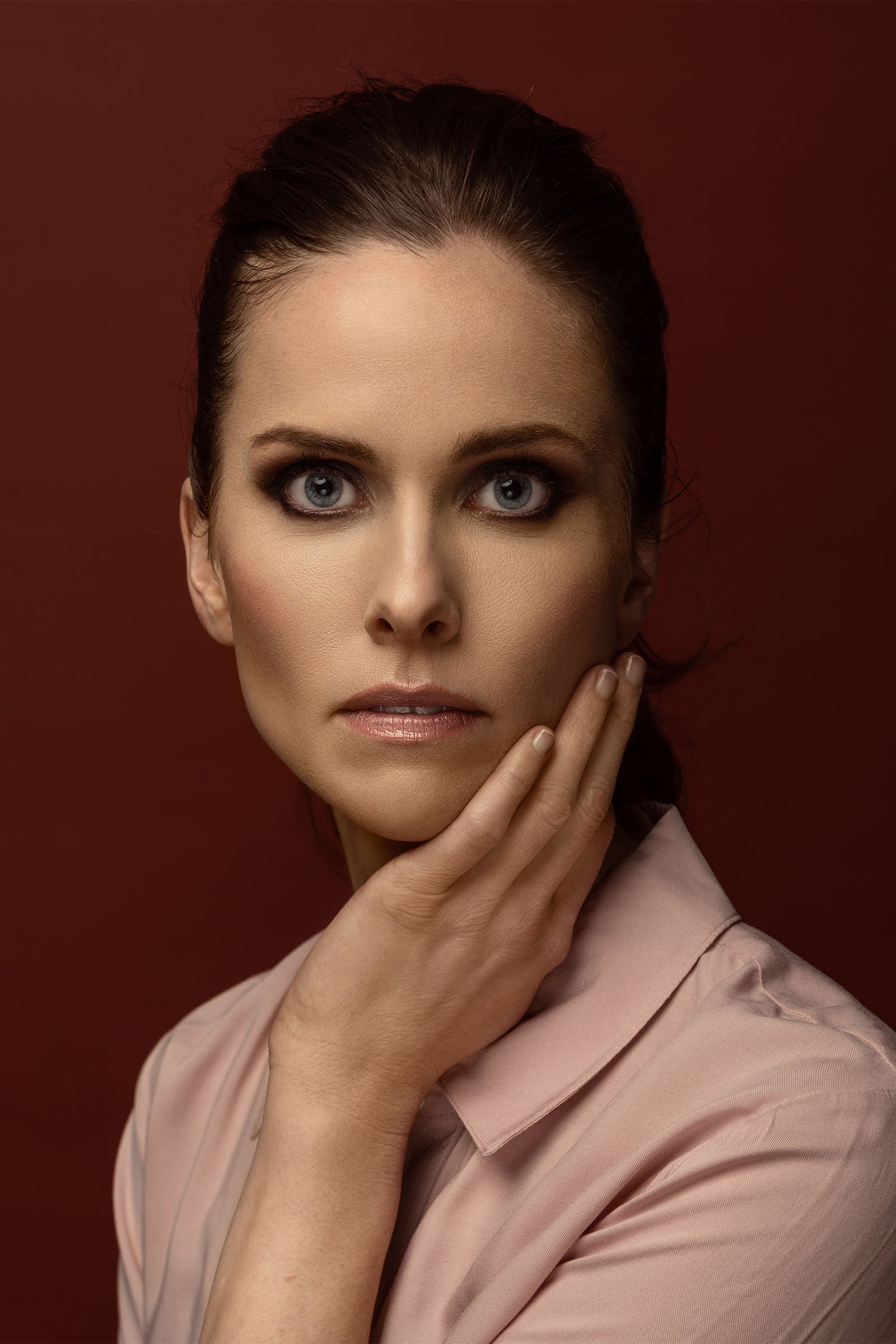 Beauty portrait of a demure female model, hand on her face, looking at the camera, mesmerizing by Utah photographer Christopher Loke